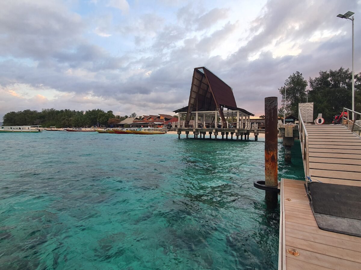 Wooden dock and arrival terminal at Gili Meno port with turquoise waters and tropical scenery