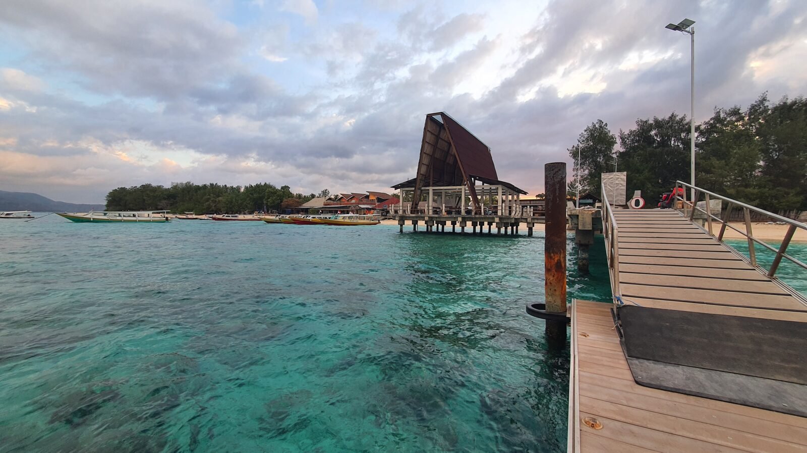 Wooden dock and arrival terminal at Gili Meno port with turquoise waters and tropical scenery