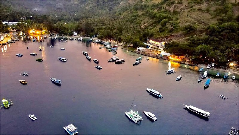 Aerial view of Teluk Nare Port in Lombok with boats anchored along the shoreline during sunset