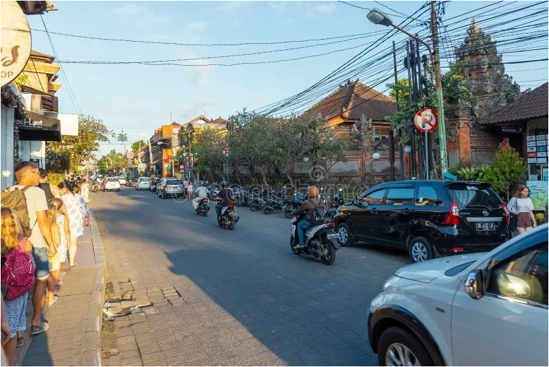 Busy street in Ubud with pedestrians, motorbikes, and traditional Balinese architecture